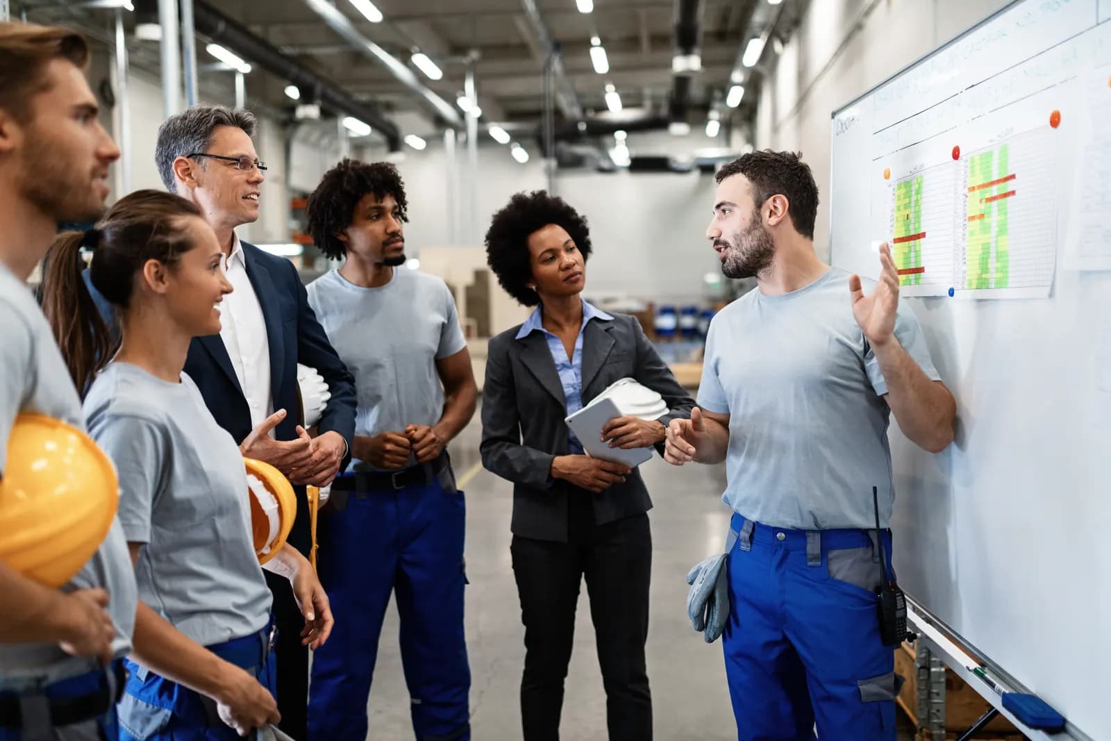 A site supervisor walking a team of industrial workers through a skills board